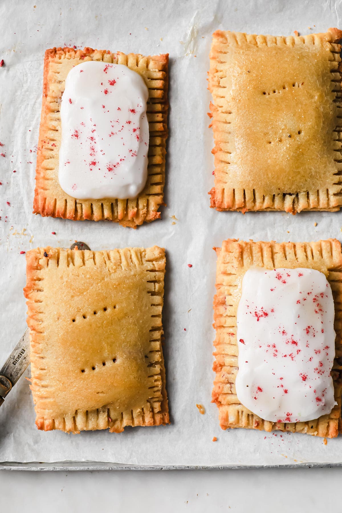 pop tarts on a baking tray - two with icing and two with an egg wash