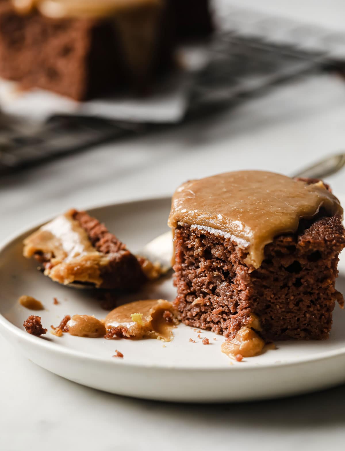 a slice of gluten free sticky toffee pudding topped with caramel sauce on a plate with a fork