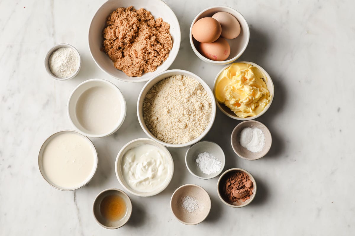 ingredients to make toffee pudding measured into bowls - almond flour, sweetener, eggs, butter and more