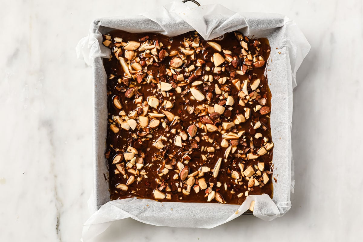 chocolate and almond topping on toffee mix in a square pan