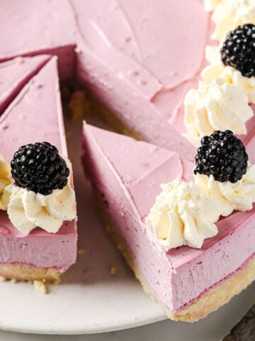 sliced keto blackberry cheesecake decorated with whipped cream rosettes and topped with fresh blackberries