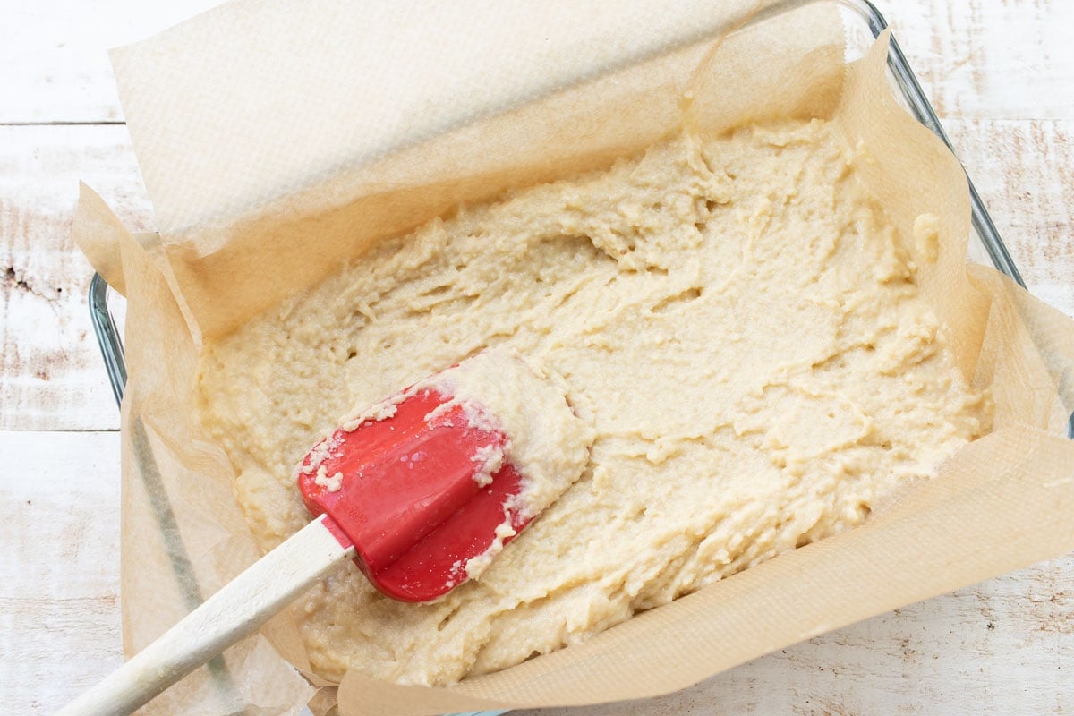yeast dough in a cake pan being smoothened with a spatula