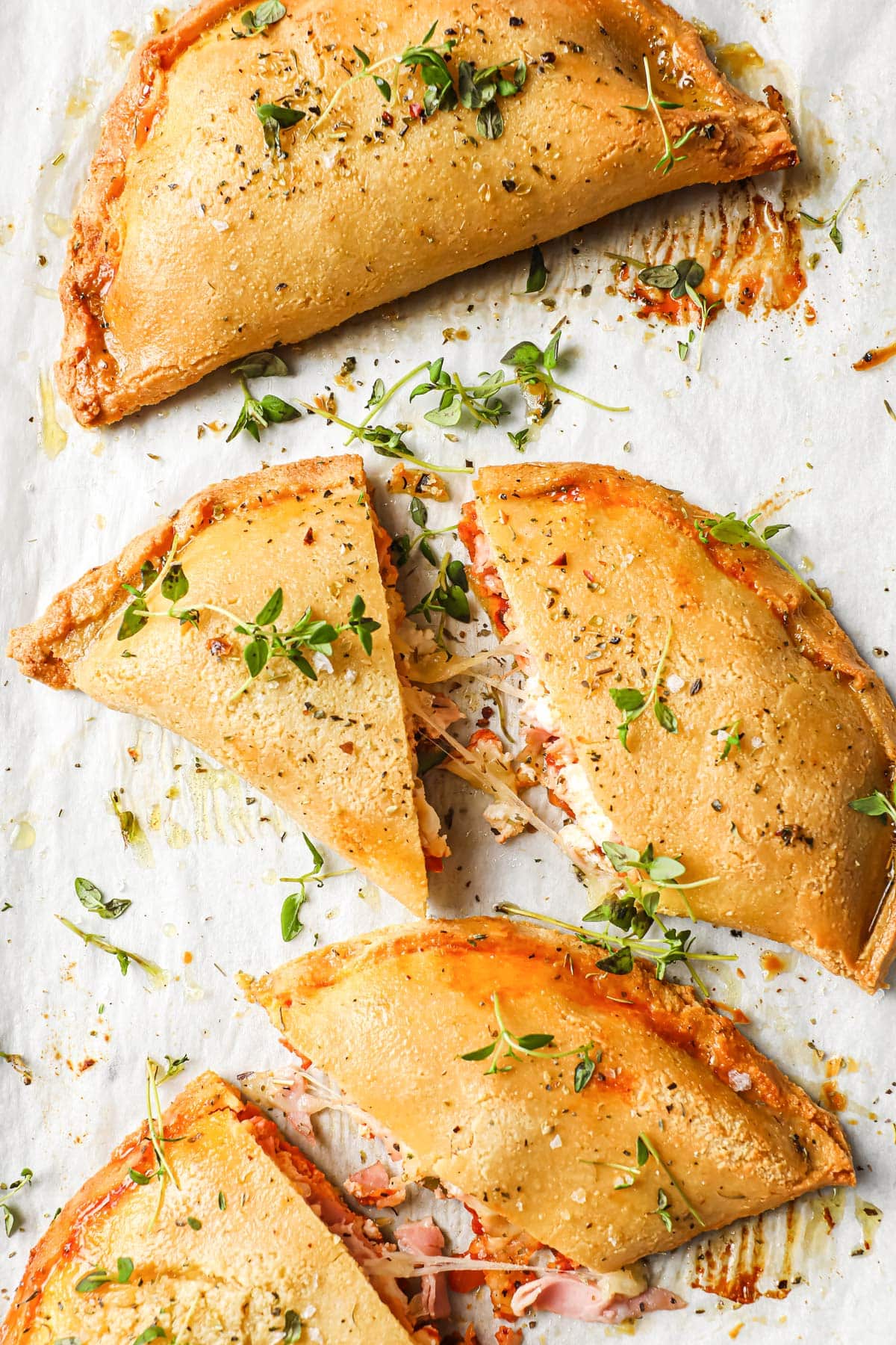 keto calzones on parchment paper and topped with thyme