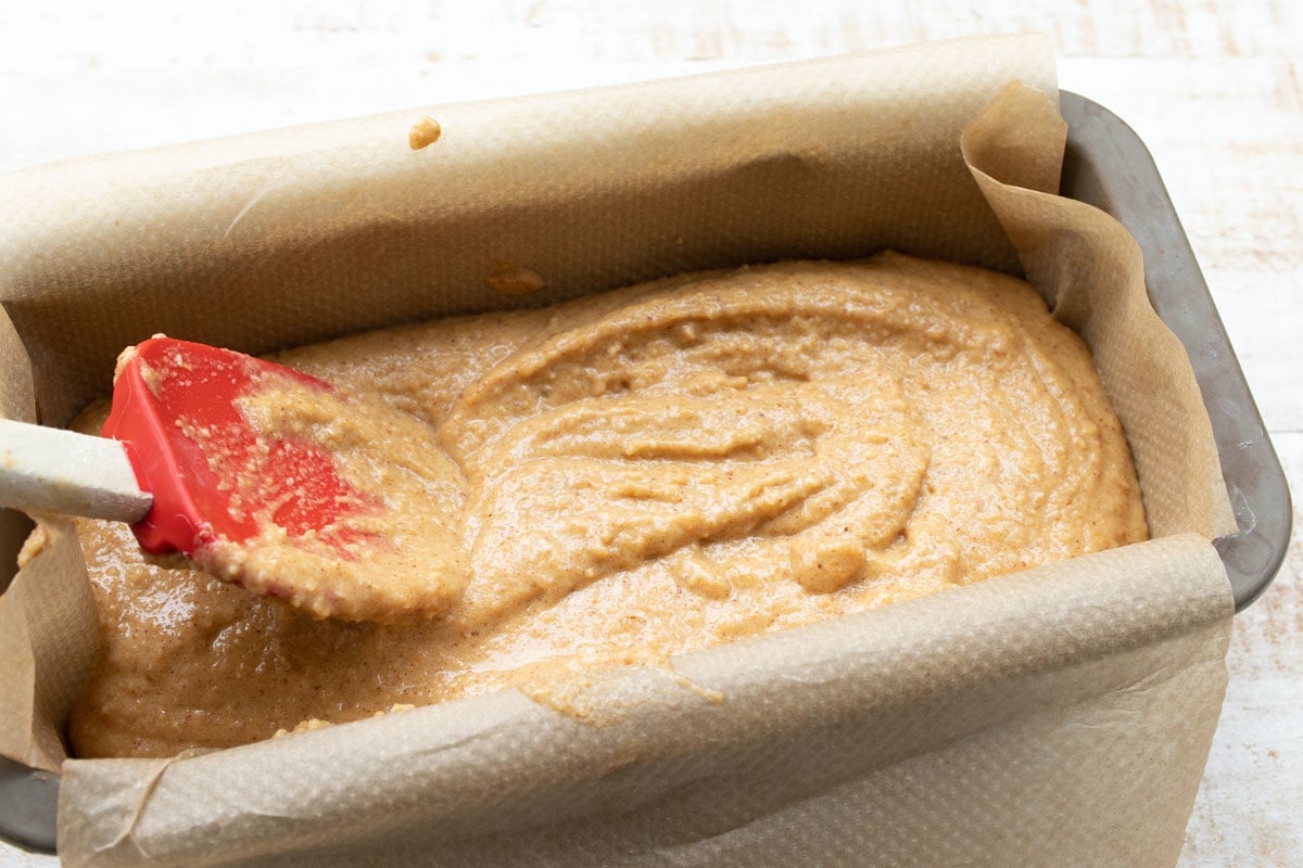 smoothing the top of the dough in a loaf tin with a spatula