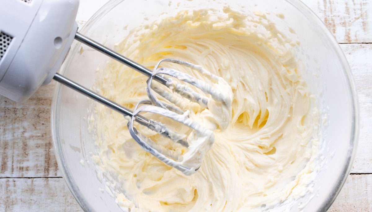 Cream cheese frosting in a bowl with an electric mixer