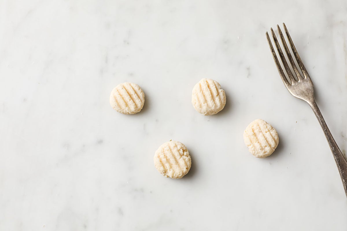 round dough shapes with fork marks and a fork
