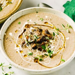 a plate with keto mushroom soup decorated with chopped mushrooms and greens