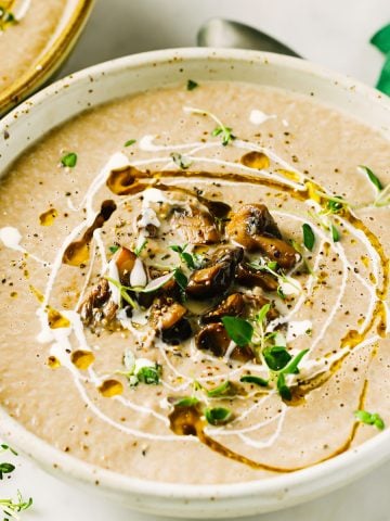 a plate with keto mushroom soup decorated with chopped mushrooms and greens