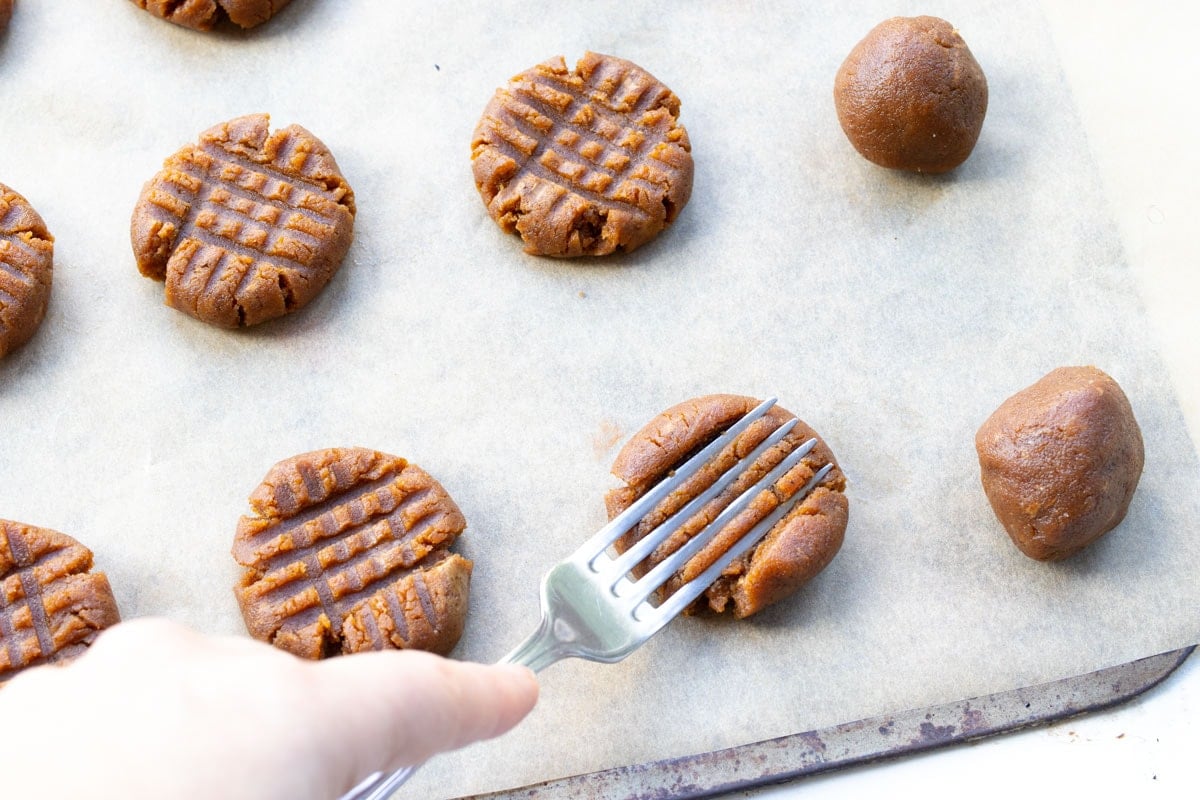 a fork making a crisscross pattern on cookie dough balls
