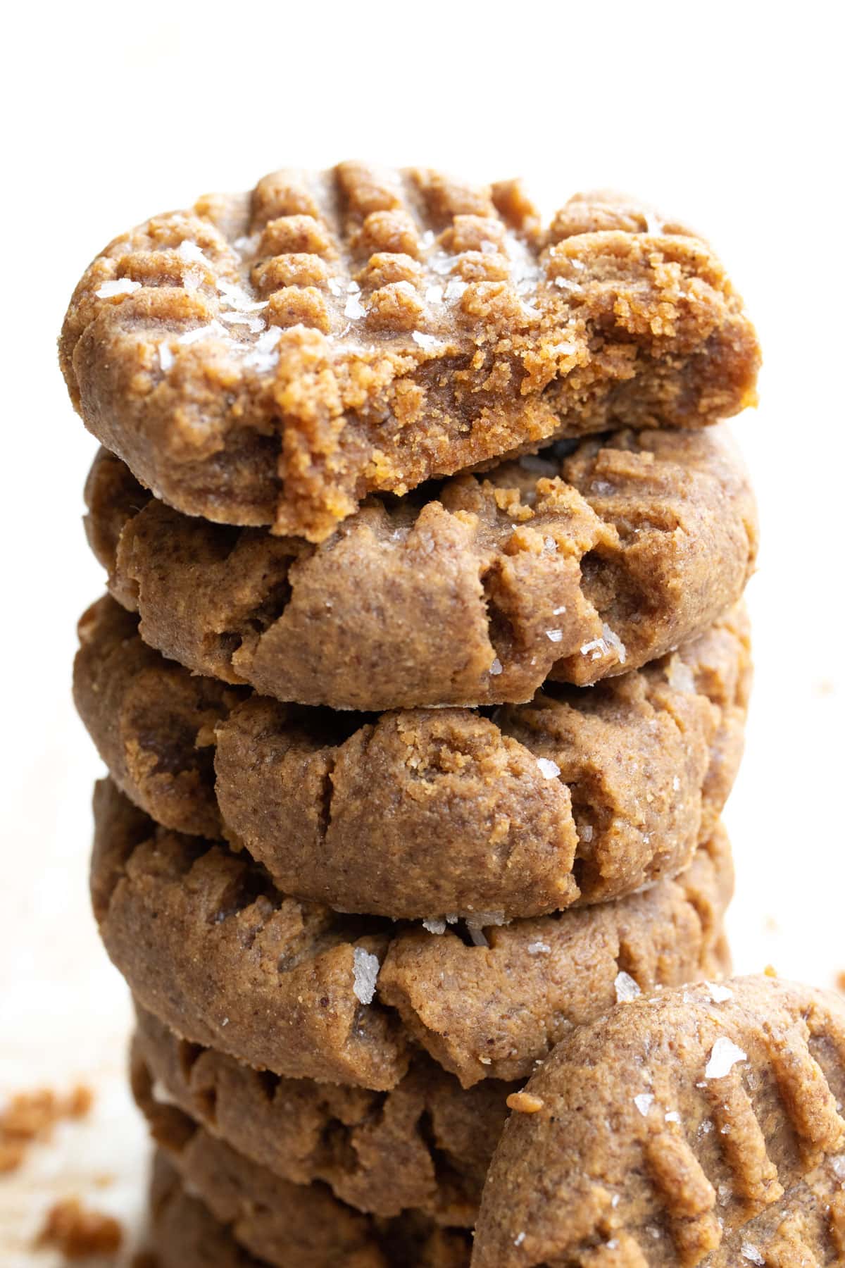 a stack of almond butter cookies topped with a bitten into cookie