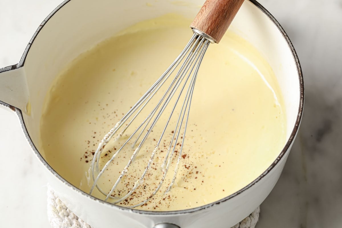 whisking nutmeg into a bechamel sauce using a balloon whisk