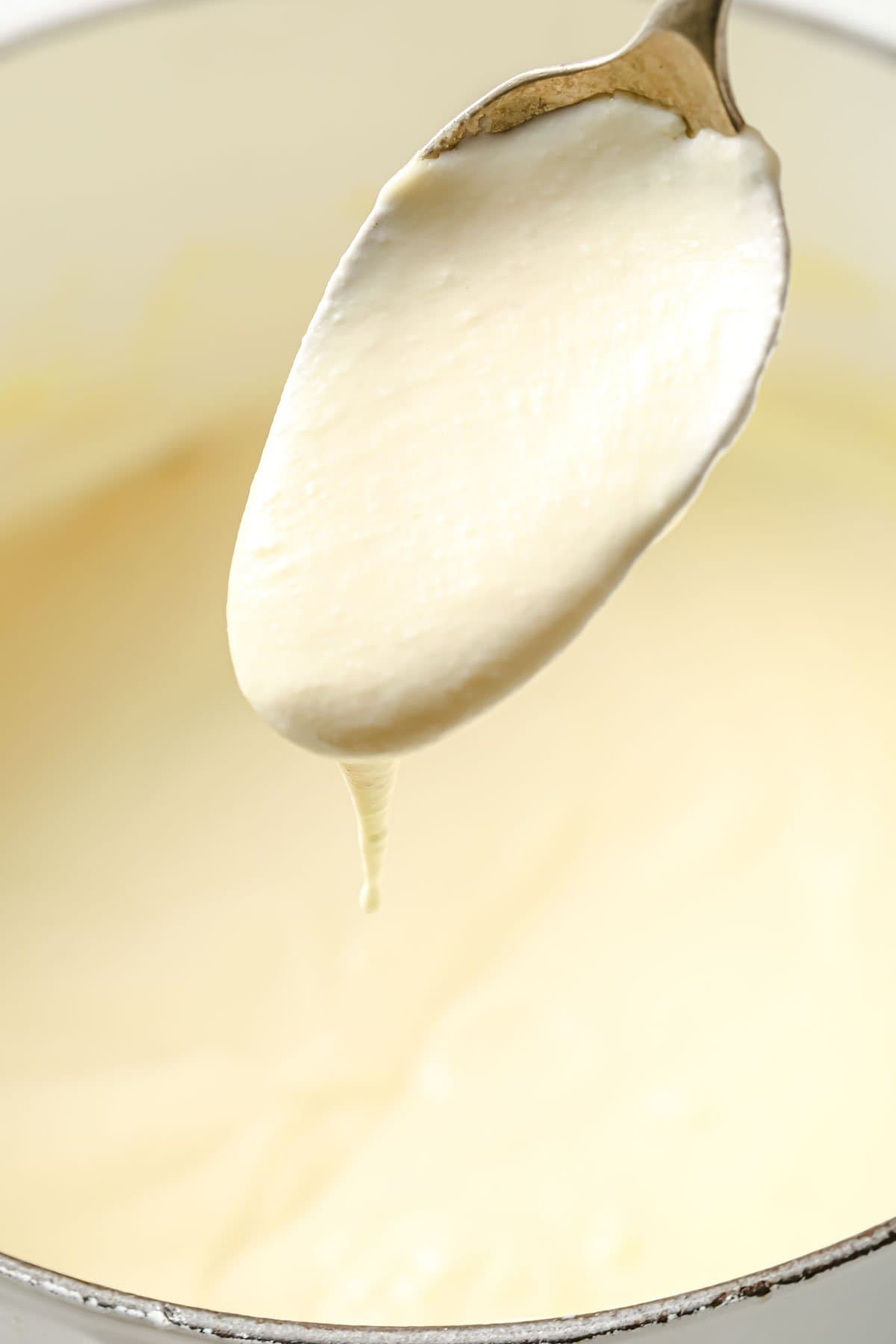 a spoon dripping with bechamel