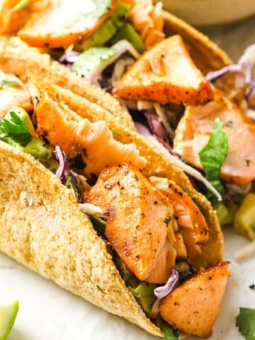 tacos willed with salmon chunks, avocado and greens