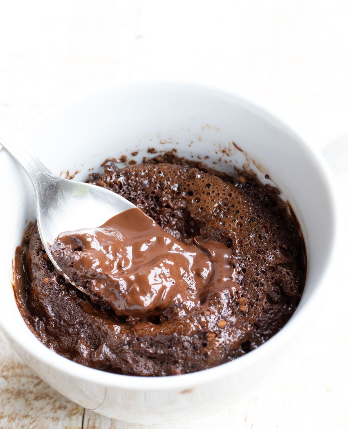 taking a spoonful from the molten centre of a keto lava cake in a mug