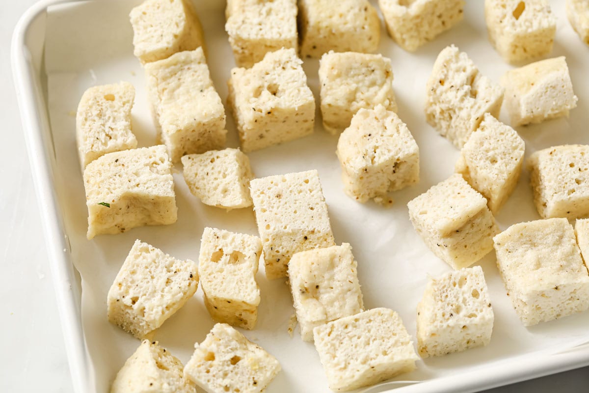 bread cut into little squares on a baking sheet