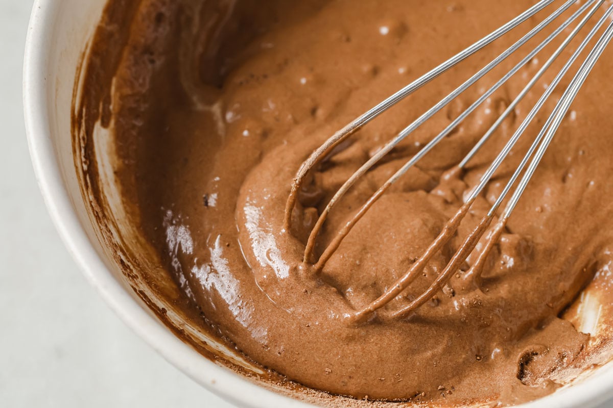 close up of a whisk in the bowl with cake batter