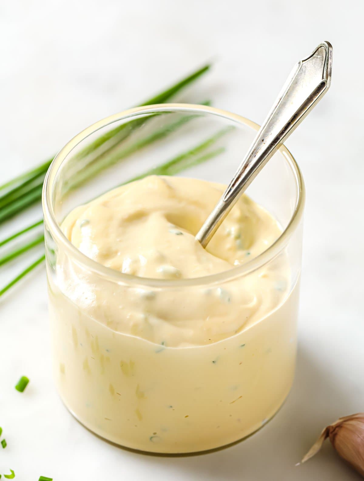 a glass with caesar dressing and a spoon