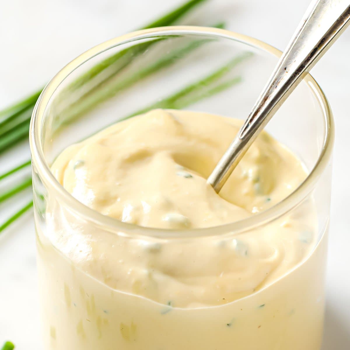 caesar dressing in a glass and a spoon