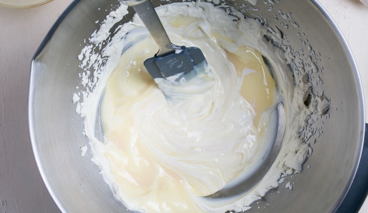 Combining cream cheese and condensed milk. 