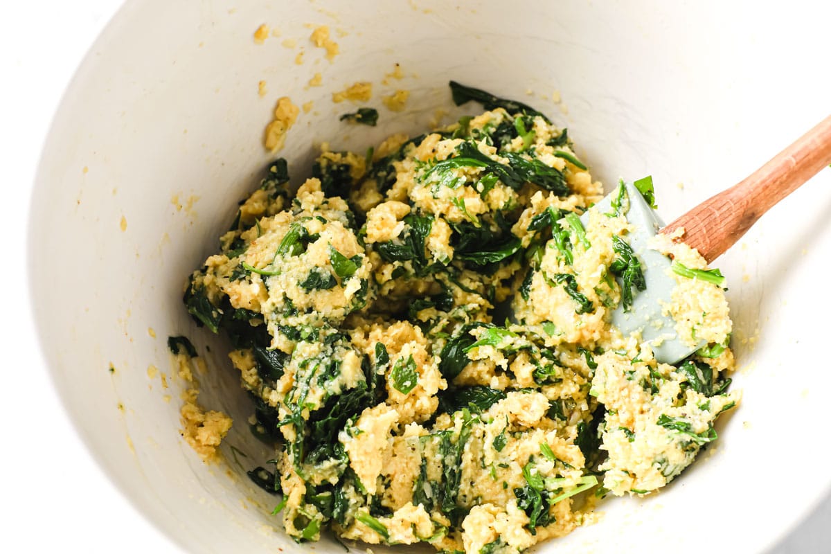 spinach mixture in a mixing bowl and a spatula