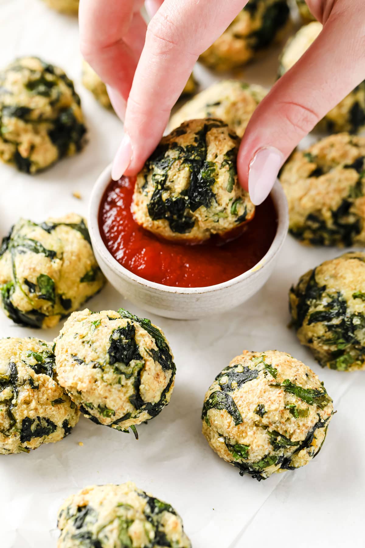 hand dipping a spinach ball in ketchup