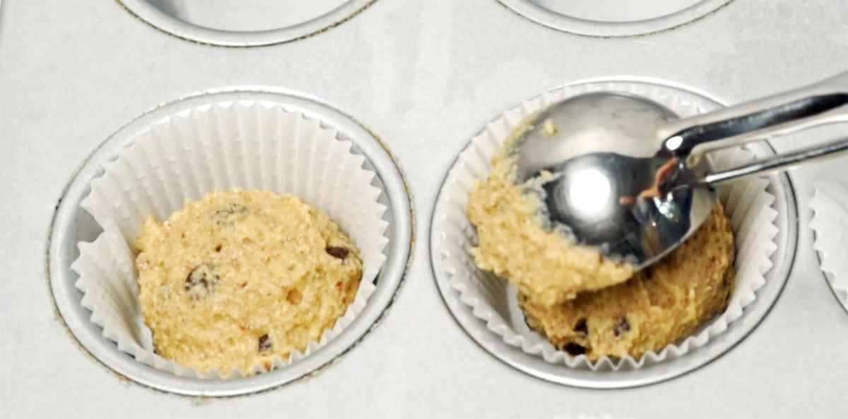 scooping muffin batter into paper liners