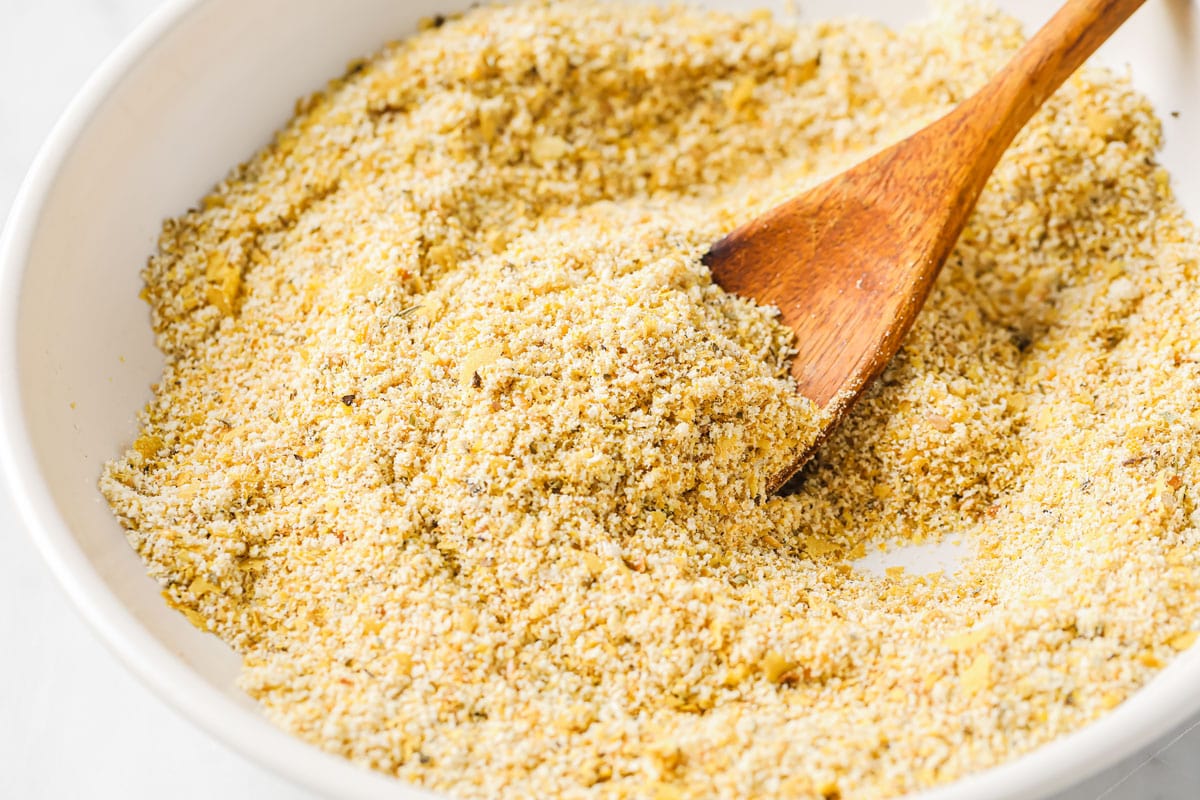 gluten-free breadcrumbs being mixed in a bowl with a wooden spoon