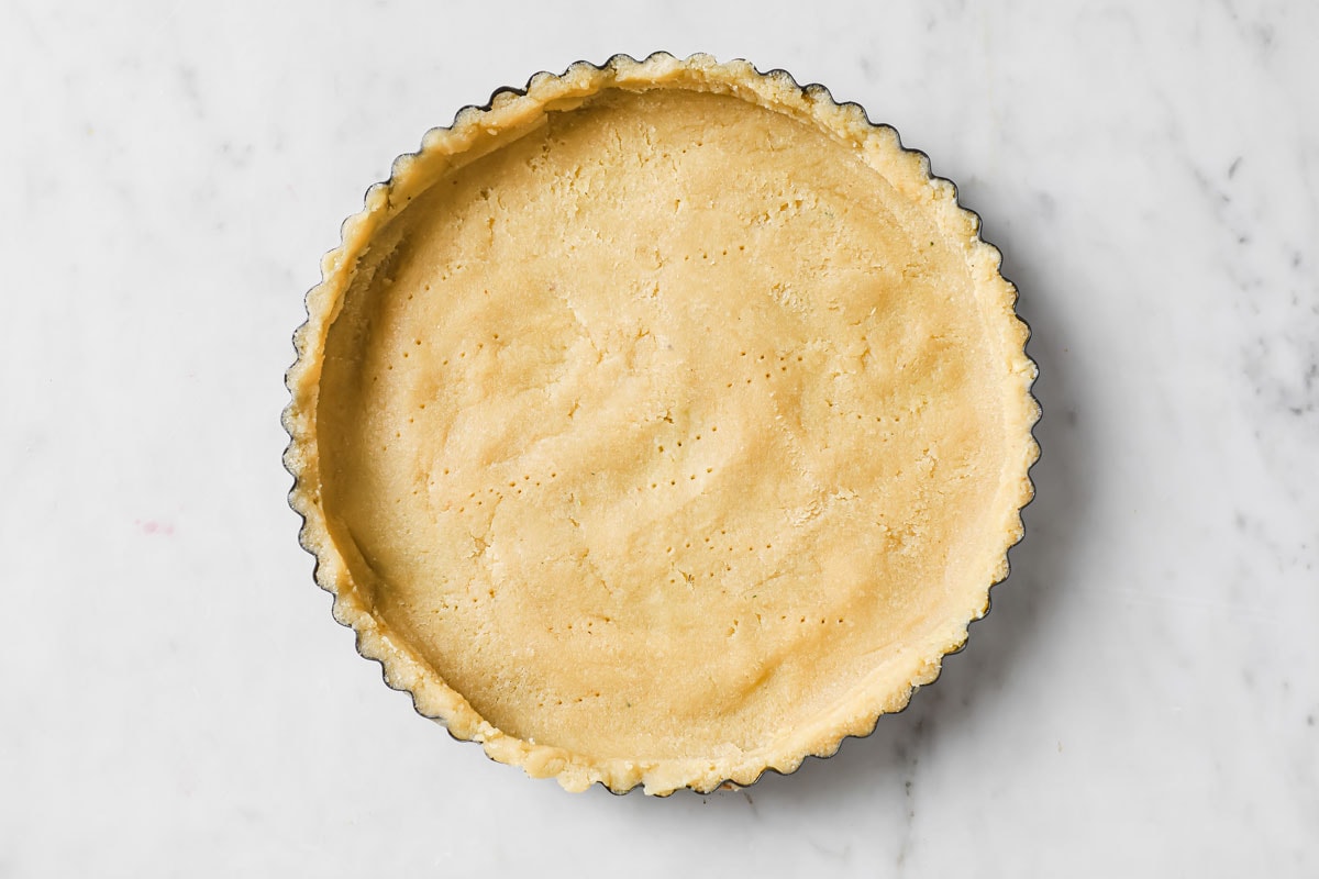 quiche crust in a pan with fork marks