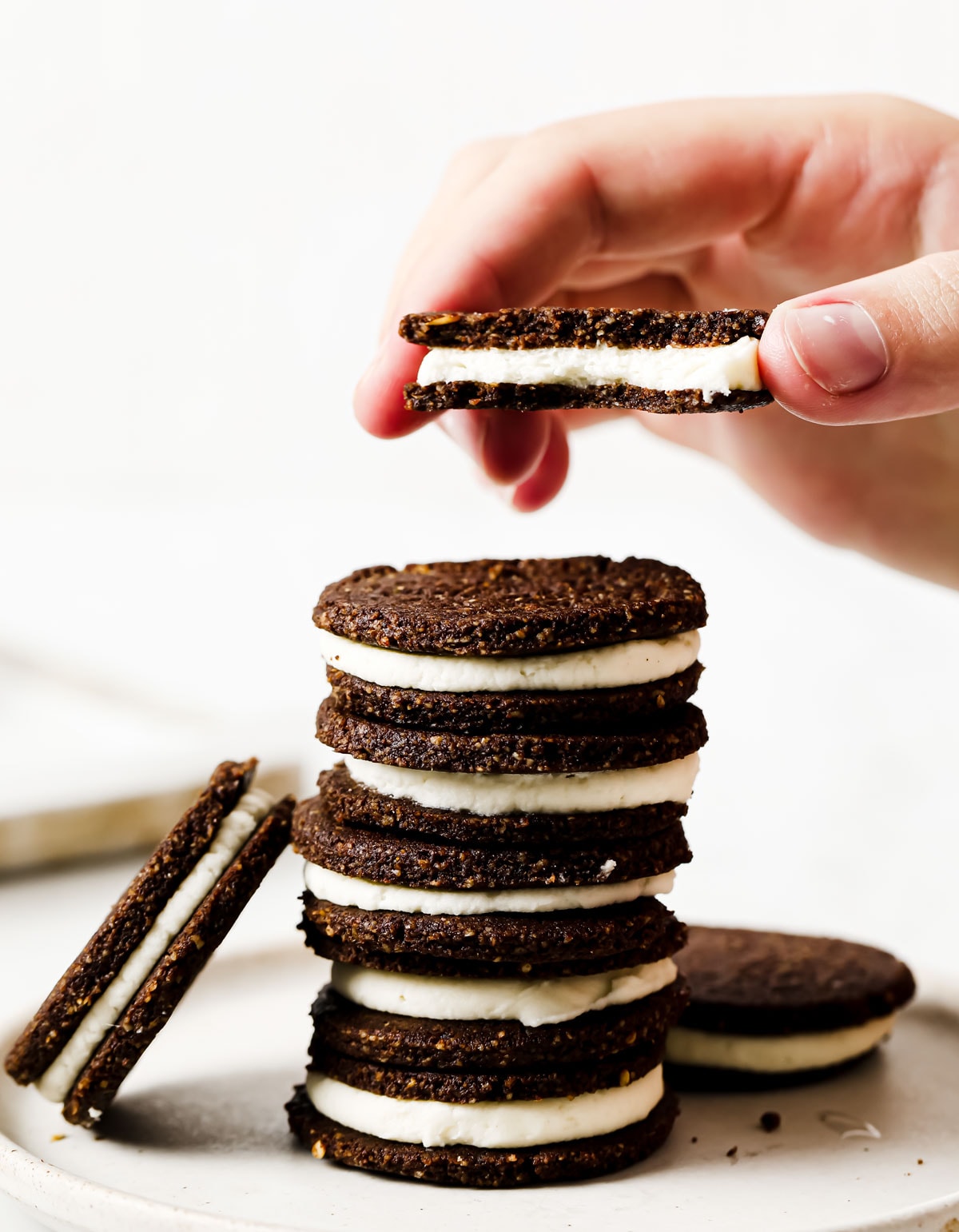 Hand lifting a cookie from a stack of cookies.