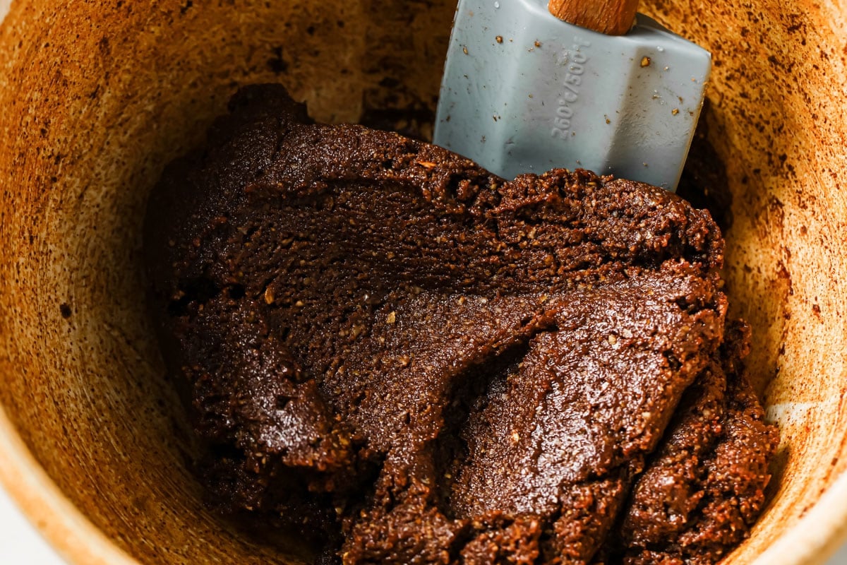 Mixing chocolate cookie dough with a spatula in a bowl.