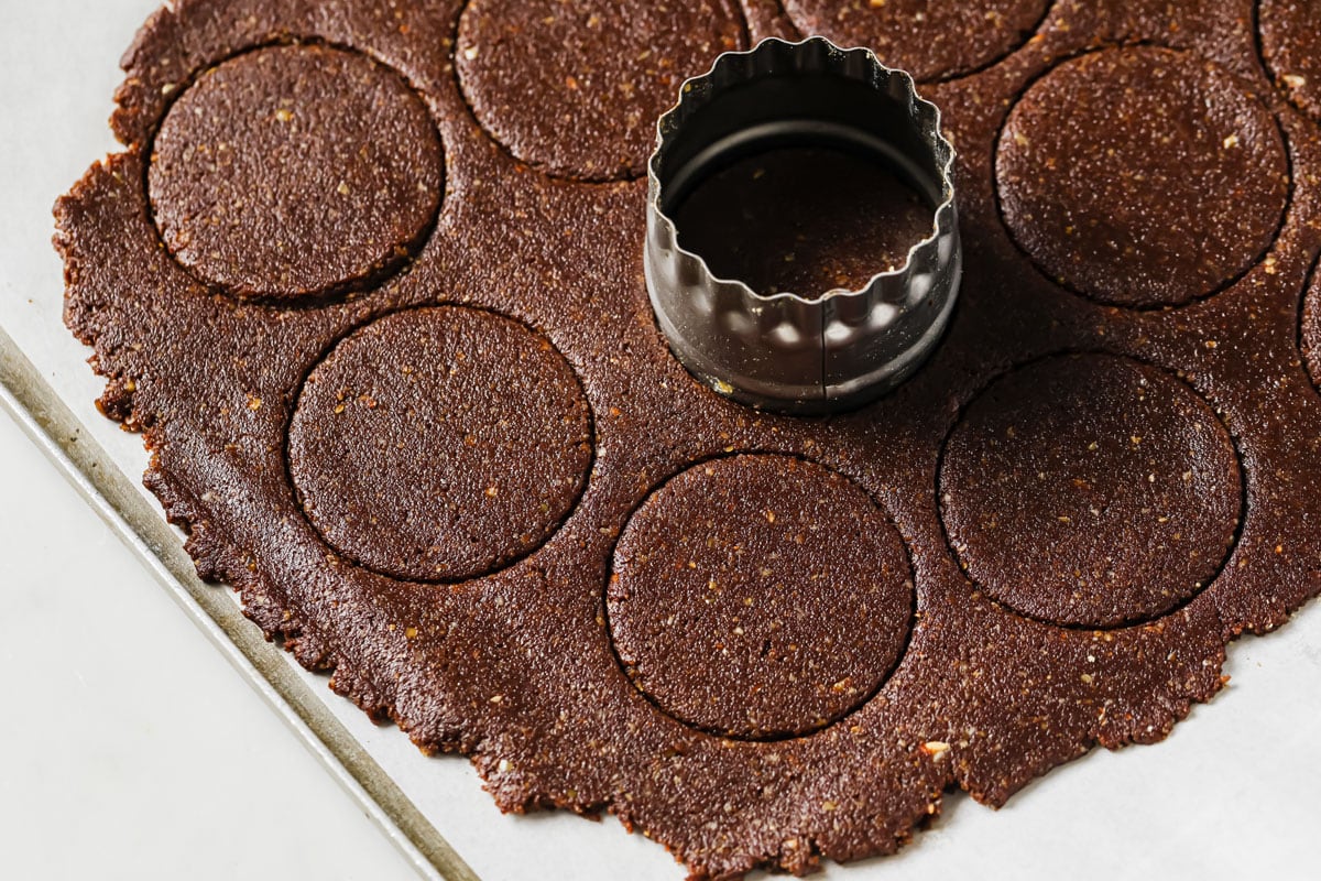 Cutting rounds of chocolate dough with a cookie cutter.