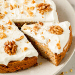 A carrot cake with frosting and walnuts.