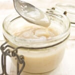 A glass jar with condensed milk and a spoon.