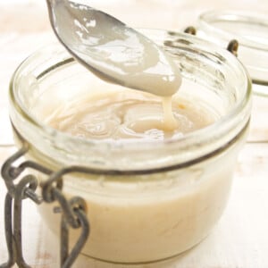A glass jar with condensed milk and a spoon.