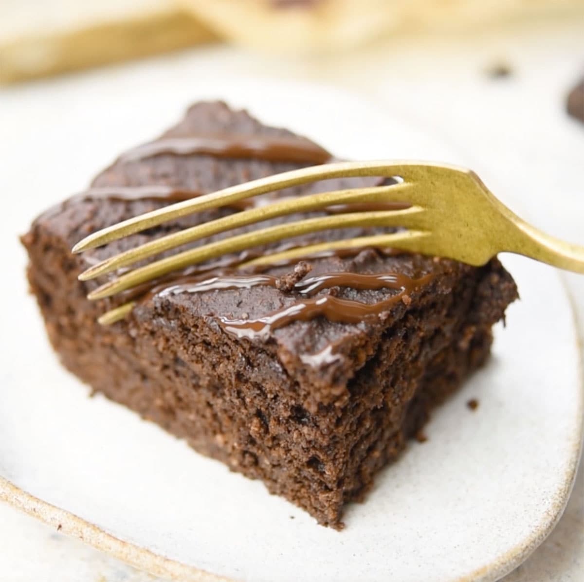 A brownie square on a plate with a fork.