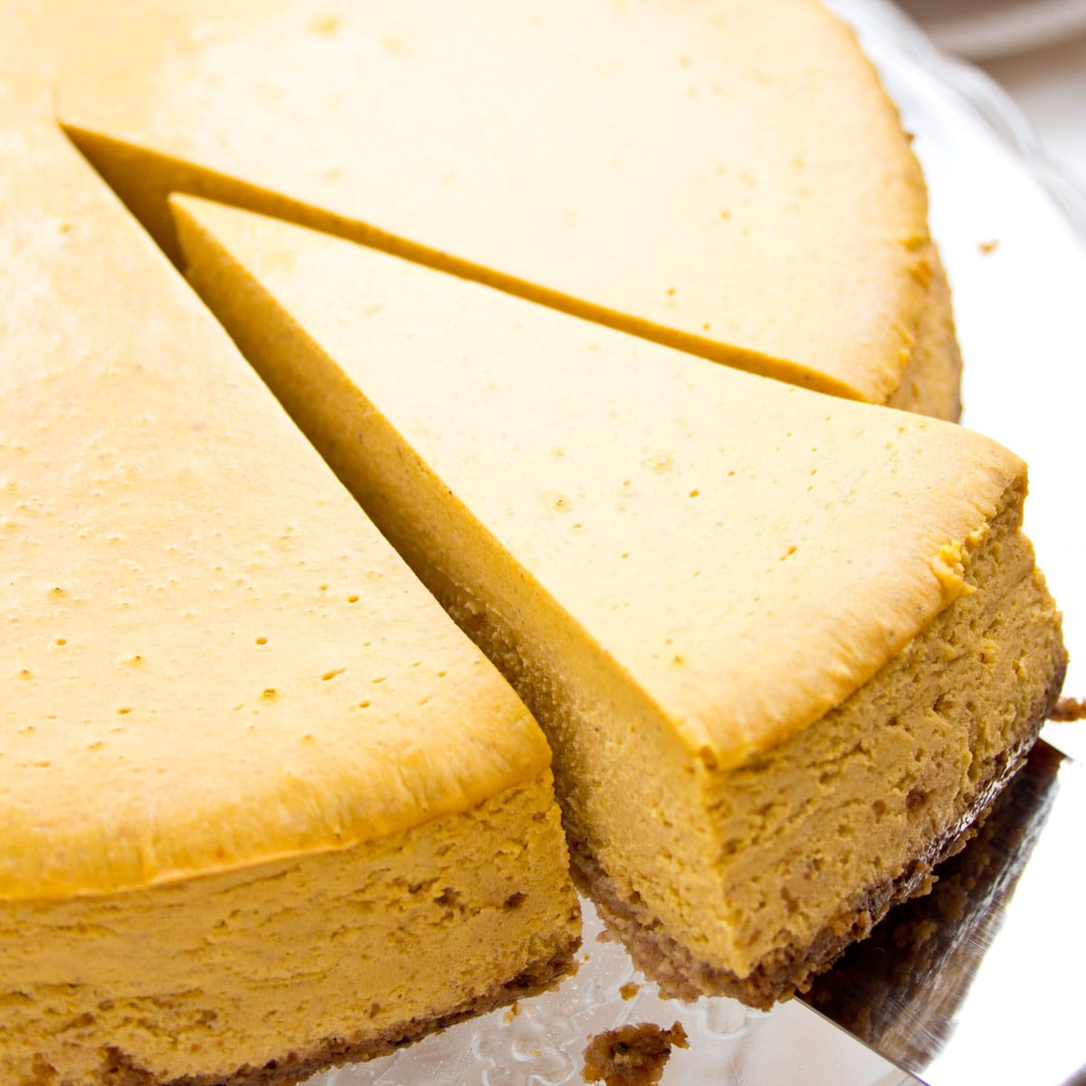 A slice of pumpkin cheesecake being lifted with a spatula.
