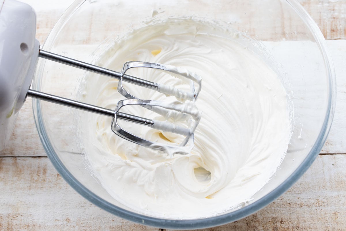 Whipped cream in a bowl with an electric mixer.