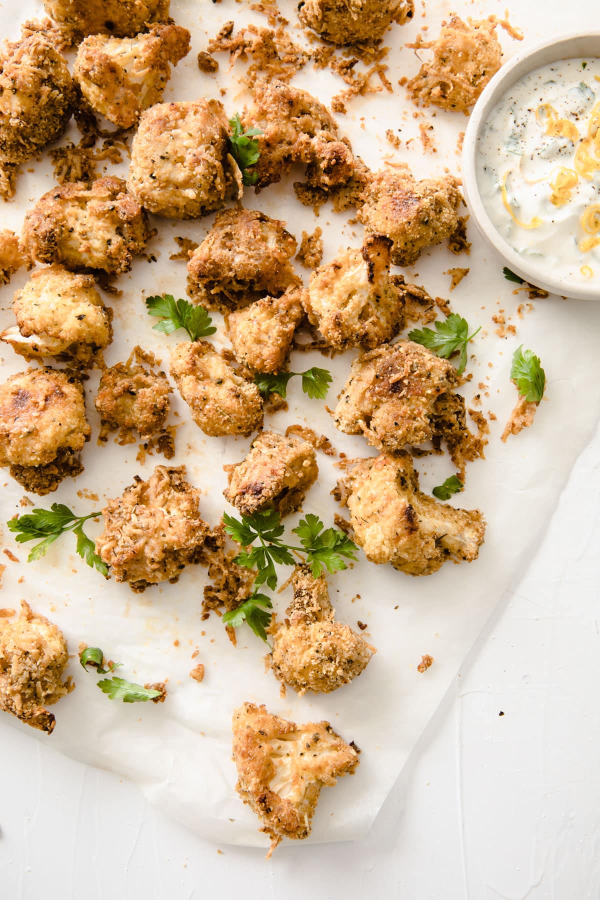 Cauliflower popcorn on parchment paper with a dip.
