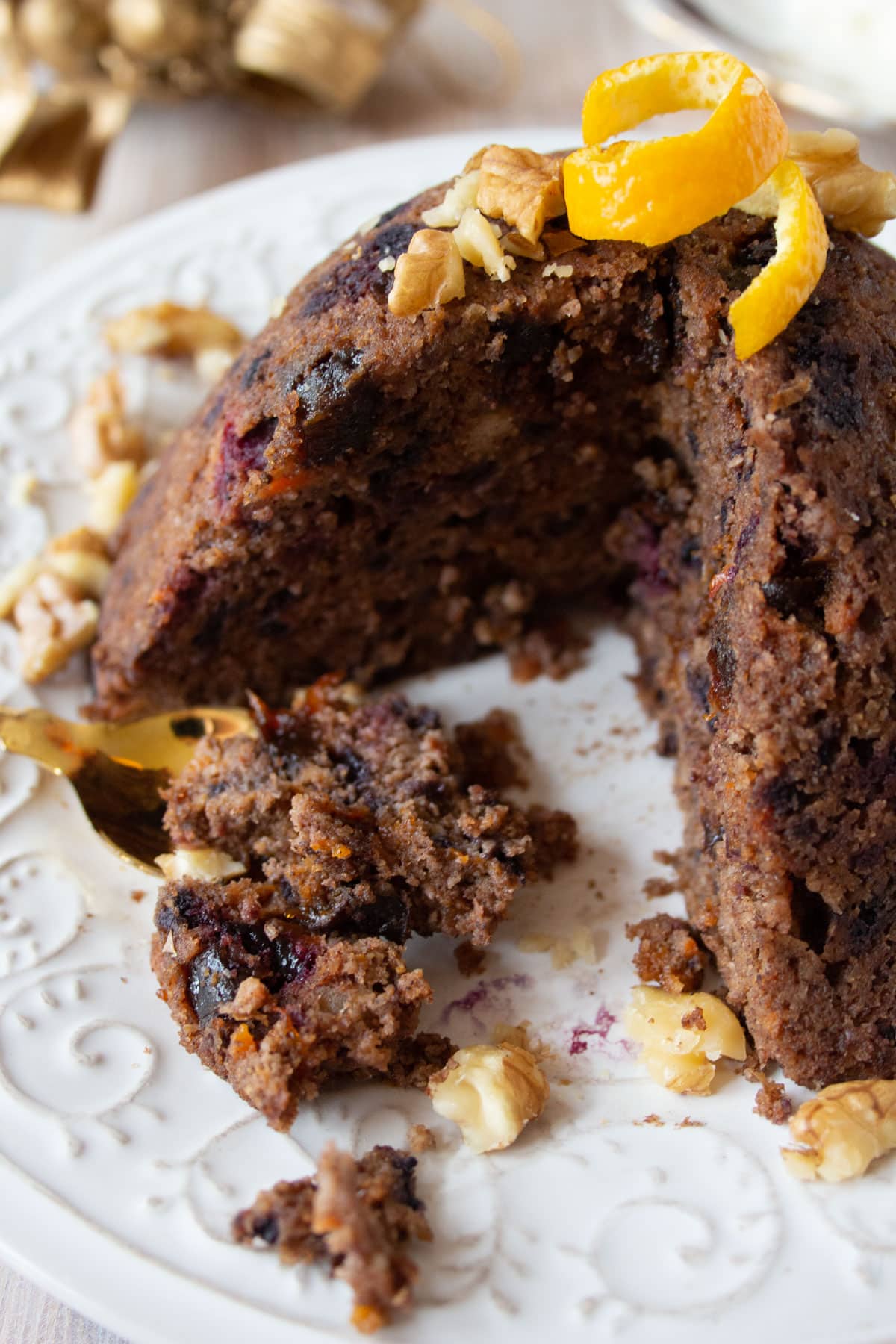 A Christmas pudding with a slice missing and pudding on a spoon.