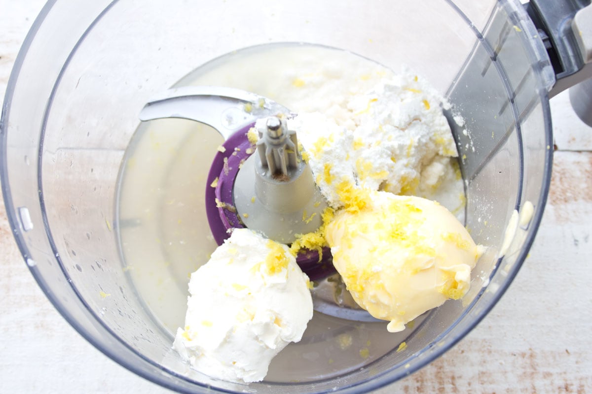 Butter, cream cheese and other ingredients in a food processor bowl.