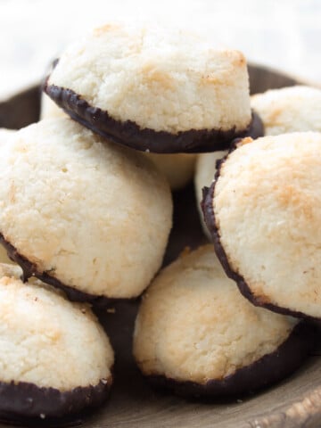 Macaroons with a chocolate bottom in a wooden bowl.