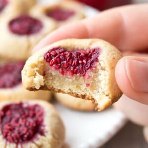 A thumbprint cookie with raspberry jam filling, bitten into.