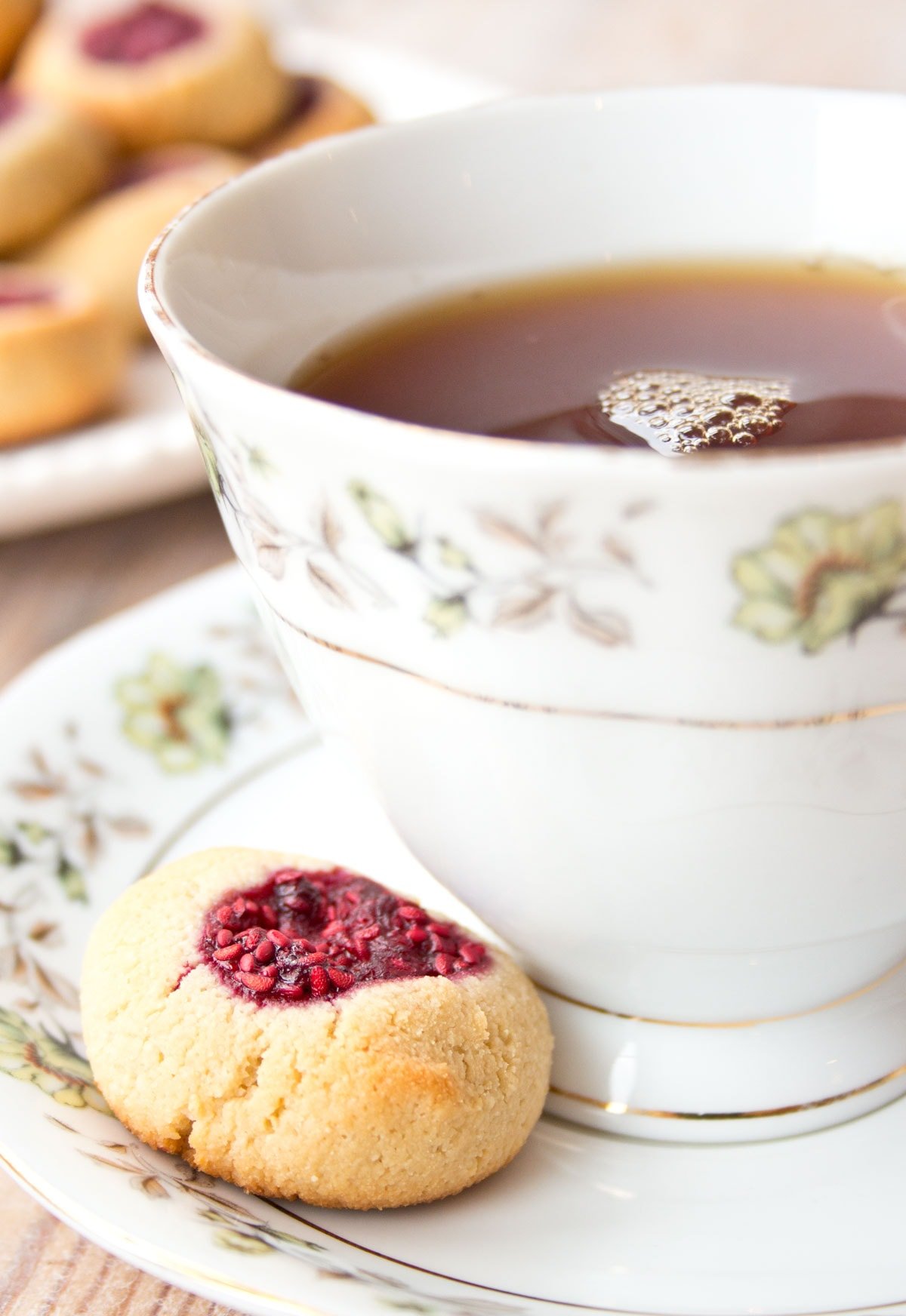 A cookie on a saucer with a cup of tea.