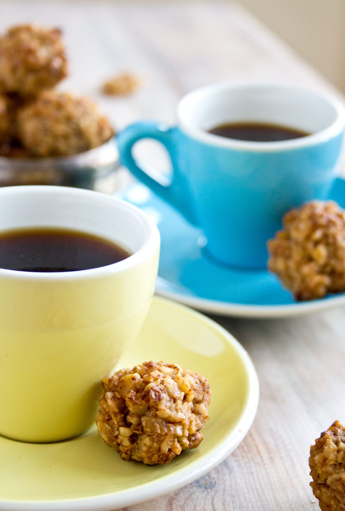 A walnut cookie on a saucer with an espresso cup.