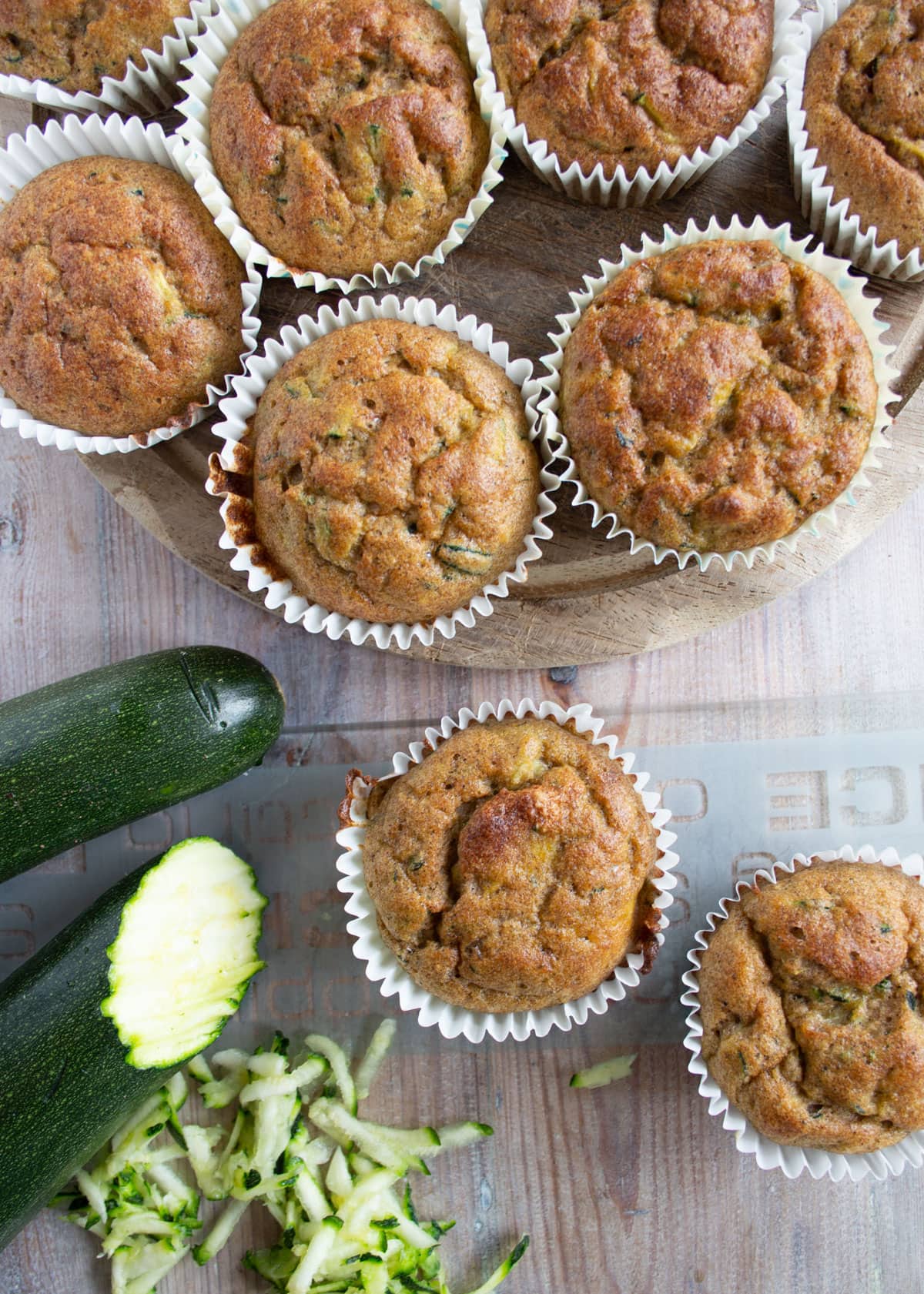 Muffins in paper cases and a zucchini, some of it grated.