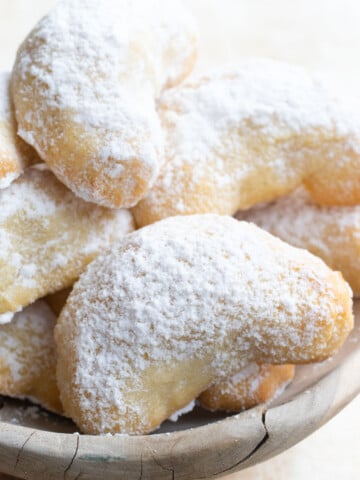Crescent shaped cookies in a bowl dusted with powdered sweeter.