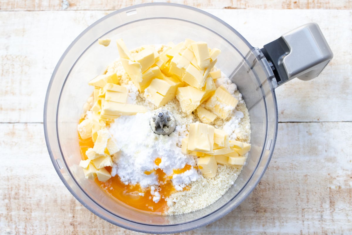 Cubed butter and other ingredients in a food processor bowl.