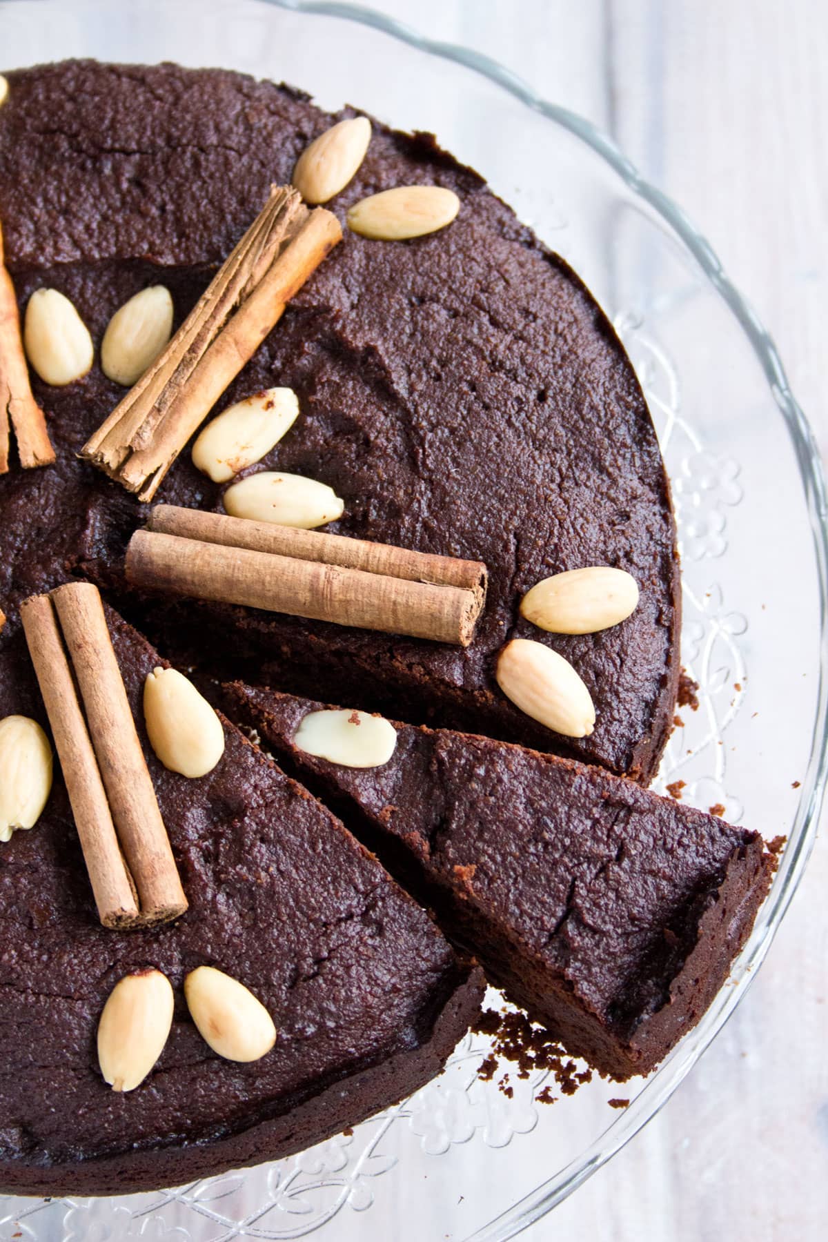 A chocolate cake decorated with almonds and cinnamon sticks.