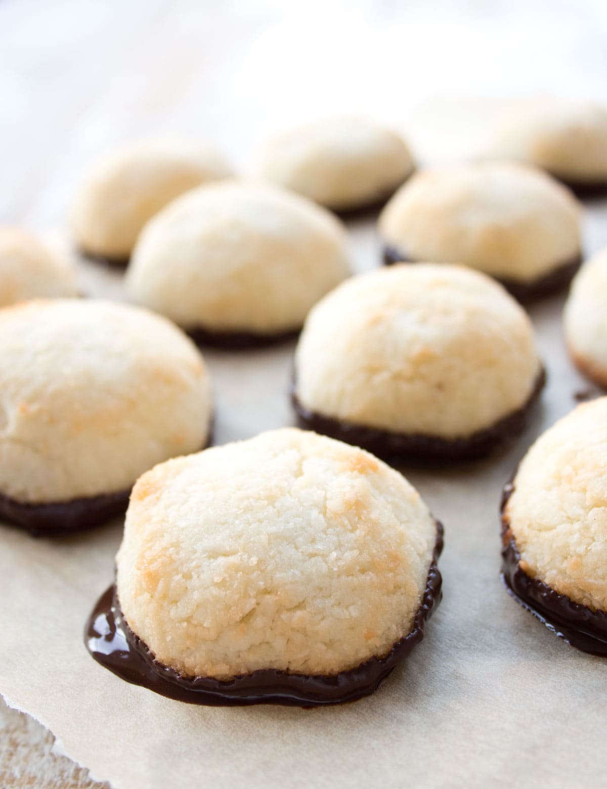 Letting the chocolate dipped macaroons cool and set on parchment paper.