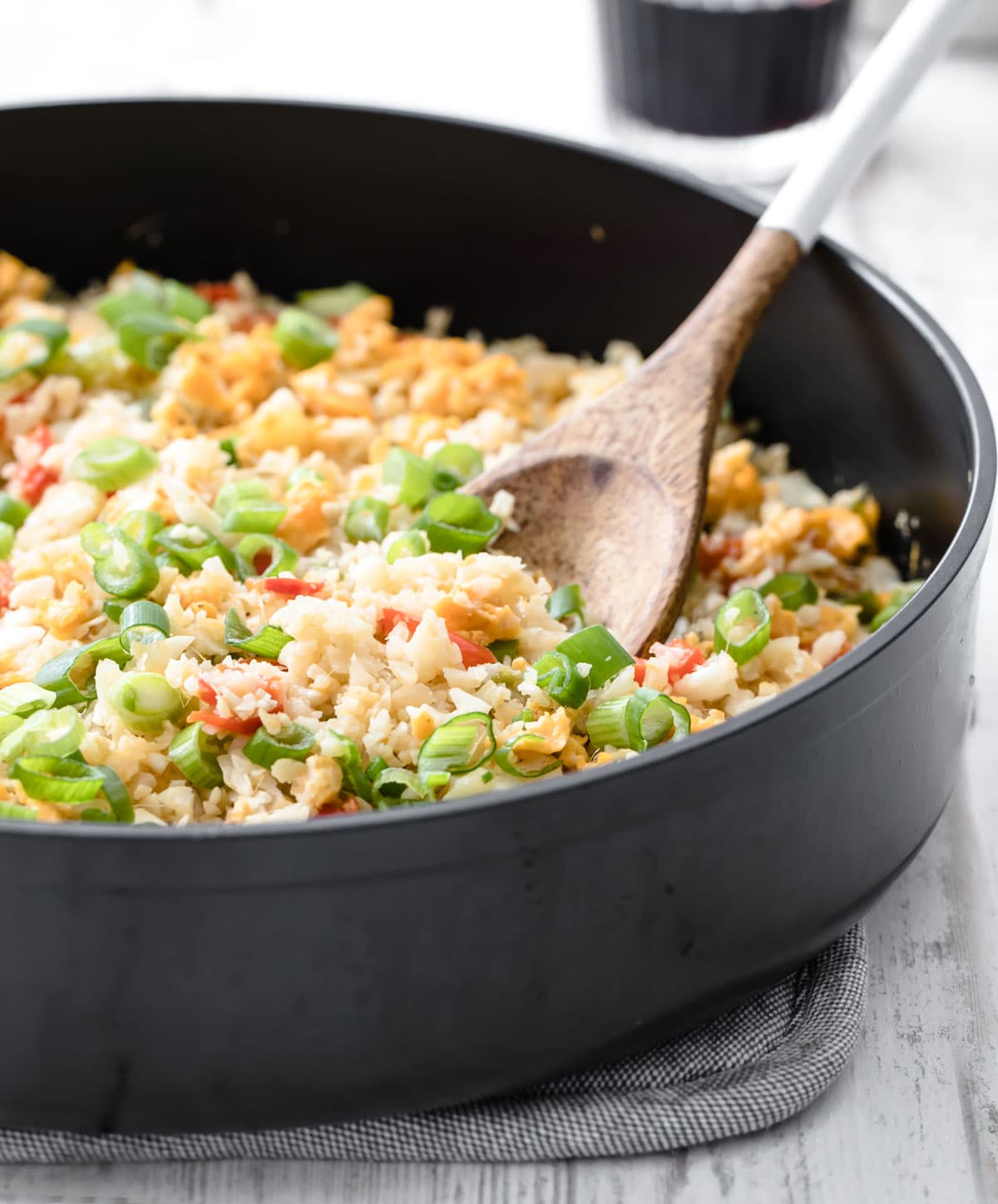 A wooden spoon in a pan with fried cauliflower rice.
